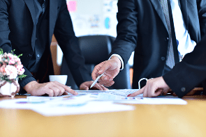 midsection-colleagues-analyzing-charts-office-desk 1